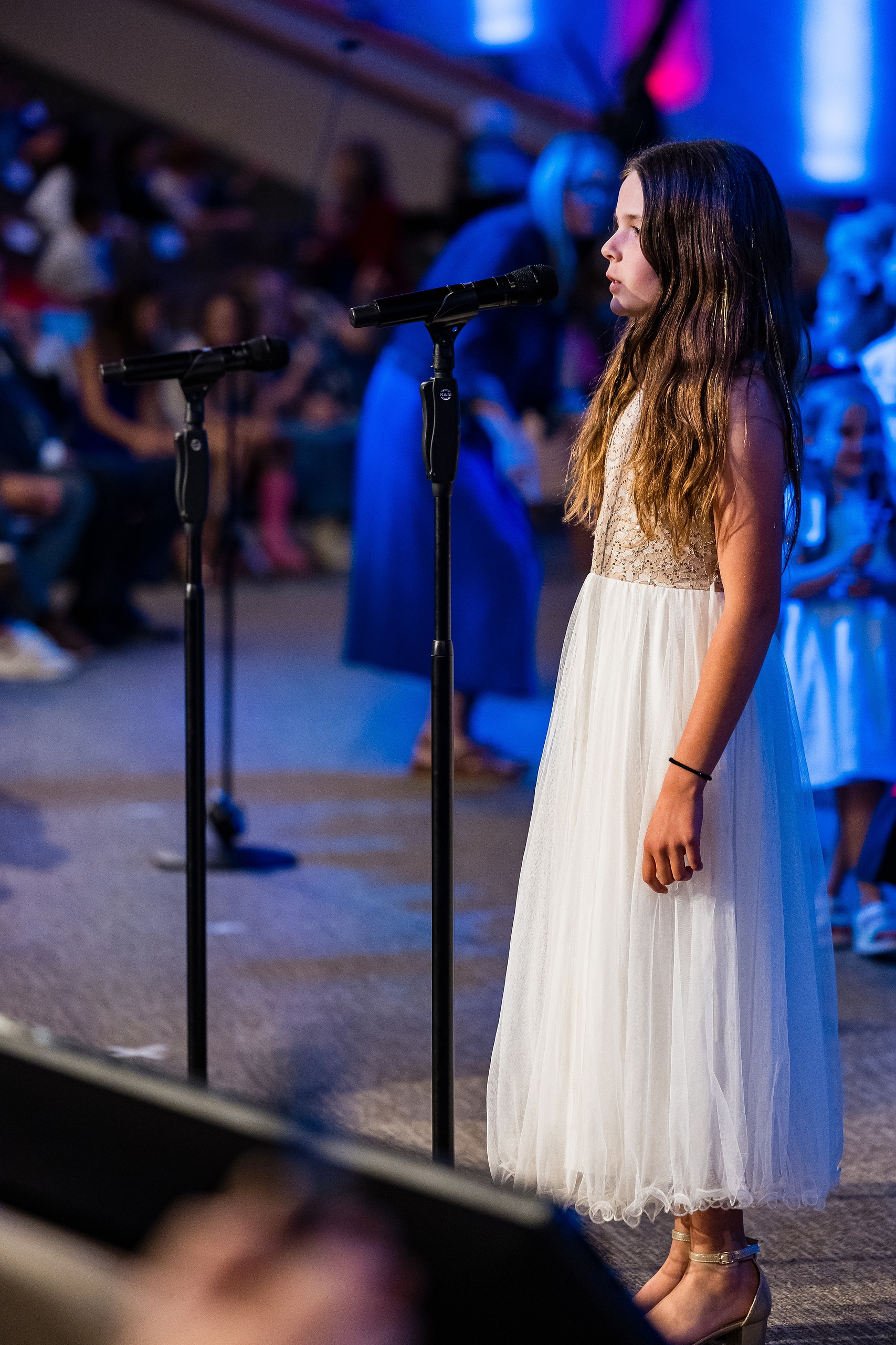Christian Elementary East Celebrates Spring with “One Nation Under God” — 17 Teen student in white formal dress singing solo at microphone