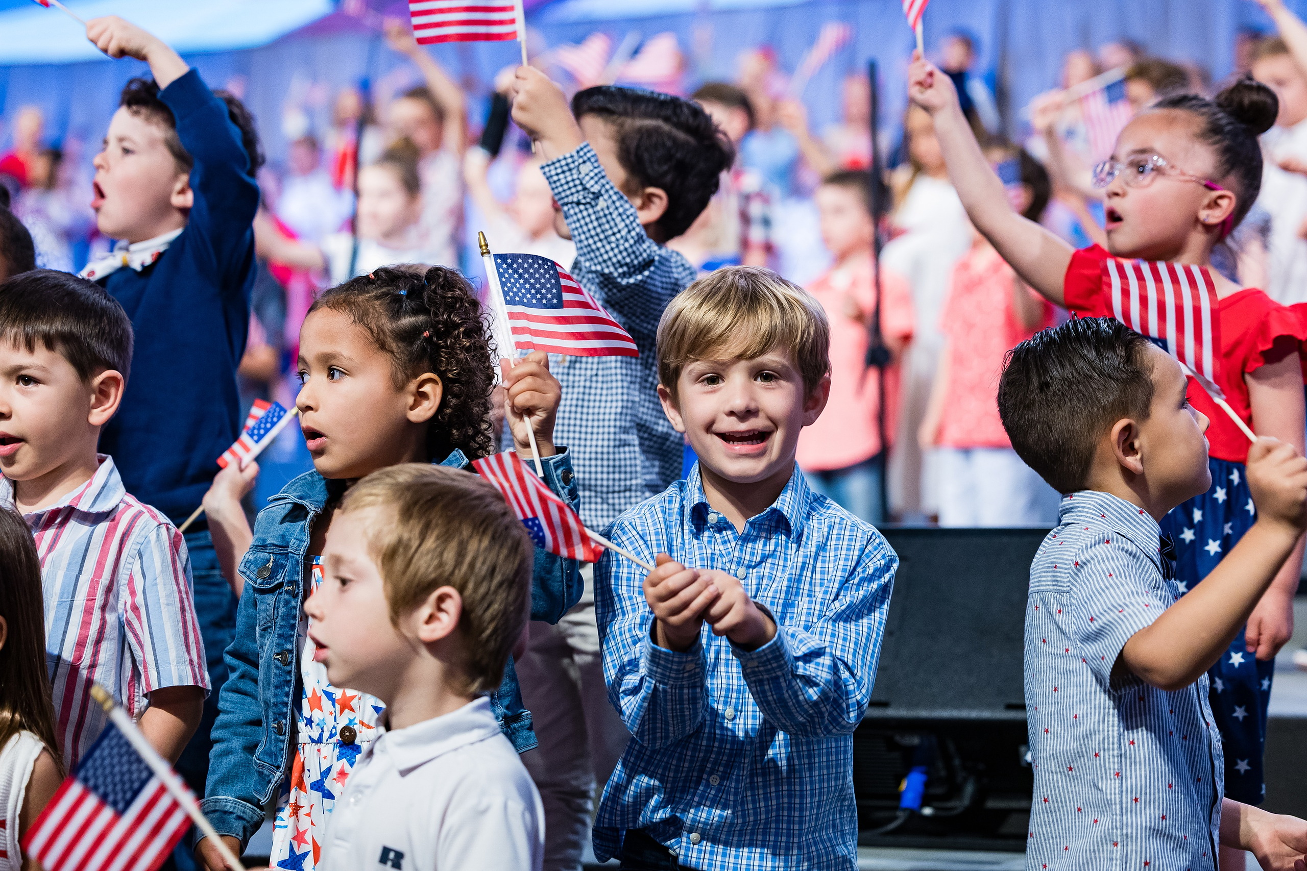Christian Elementary East Celebrates Spring with “One Nation Under God” — 20 Elementary students holding and waving American flags on stage