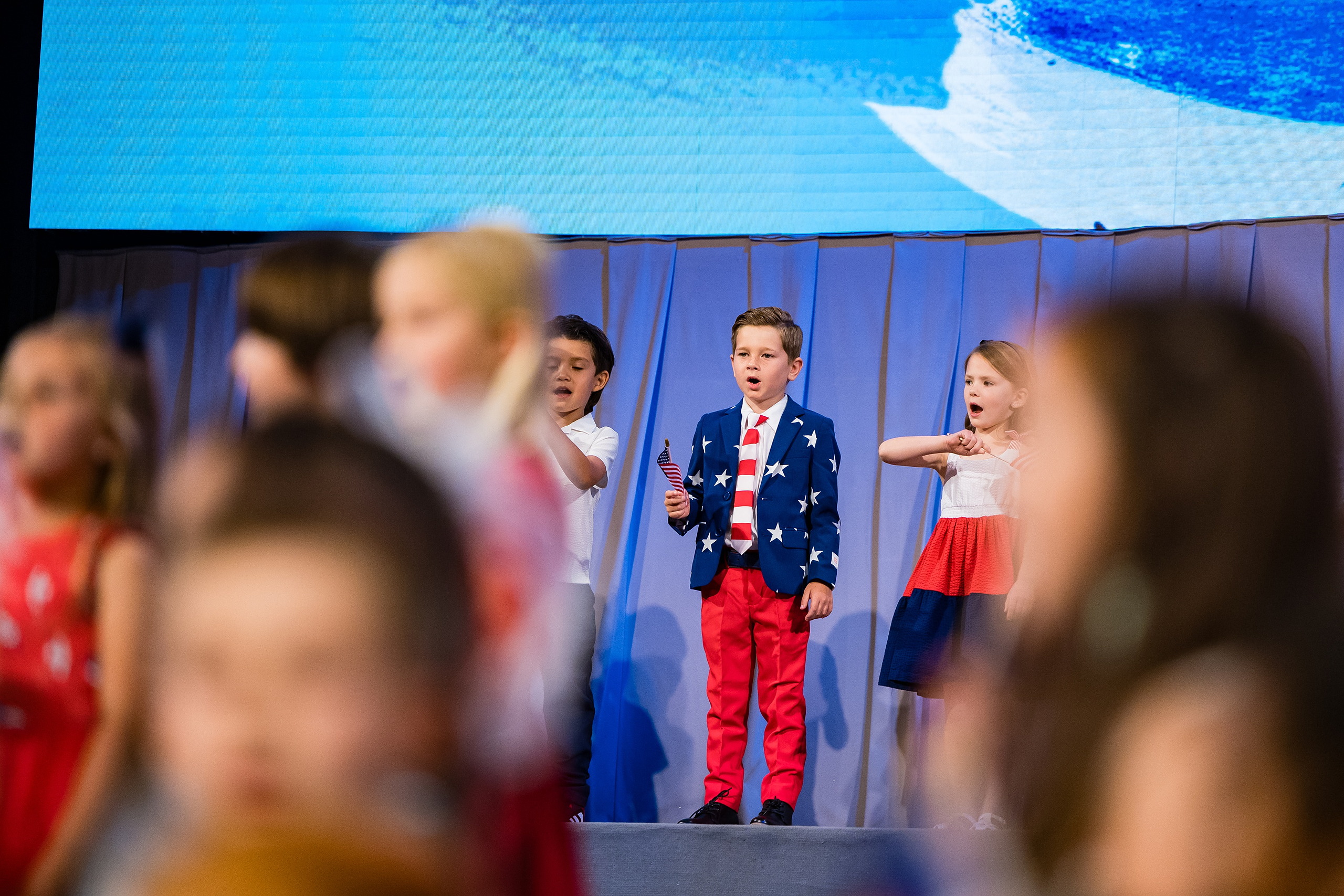 Christian Elementary East Celebrates Spring with “One Nation Under God” — 22 Student in patriotic star-print blazer featured among ensemble students