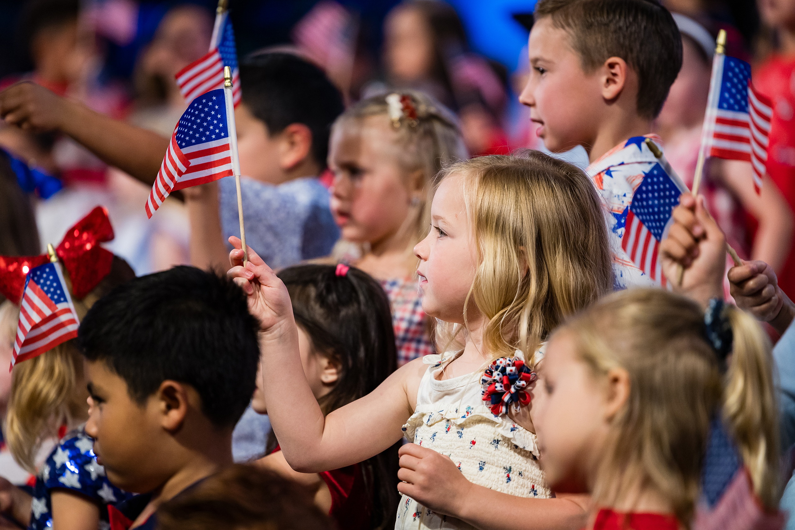 Christian Elementary East Celebrates Spring with “One Nation Under God” — 23 Close-up of children waving flags including girl with red bow