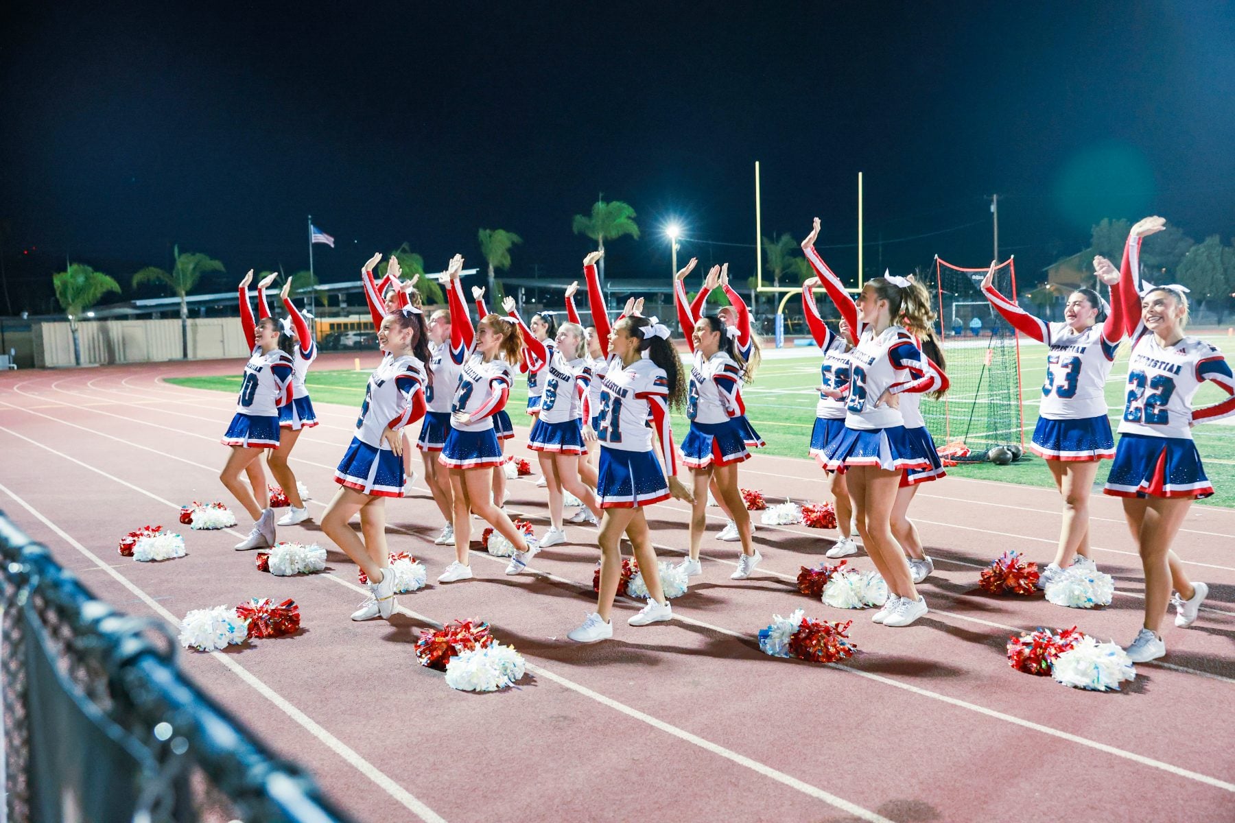 Cheerleaders wave red and blue pom poms on the track at Homecoming