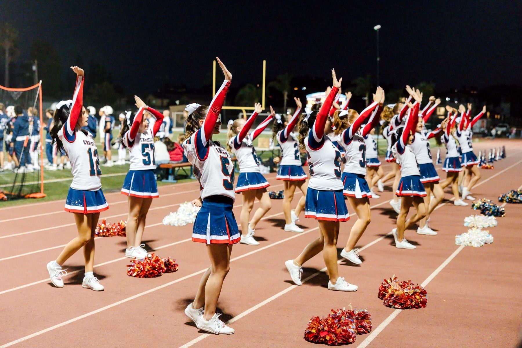 Cheerleaders raise their arms in unison during a Patriots sideline routine