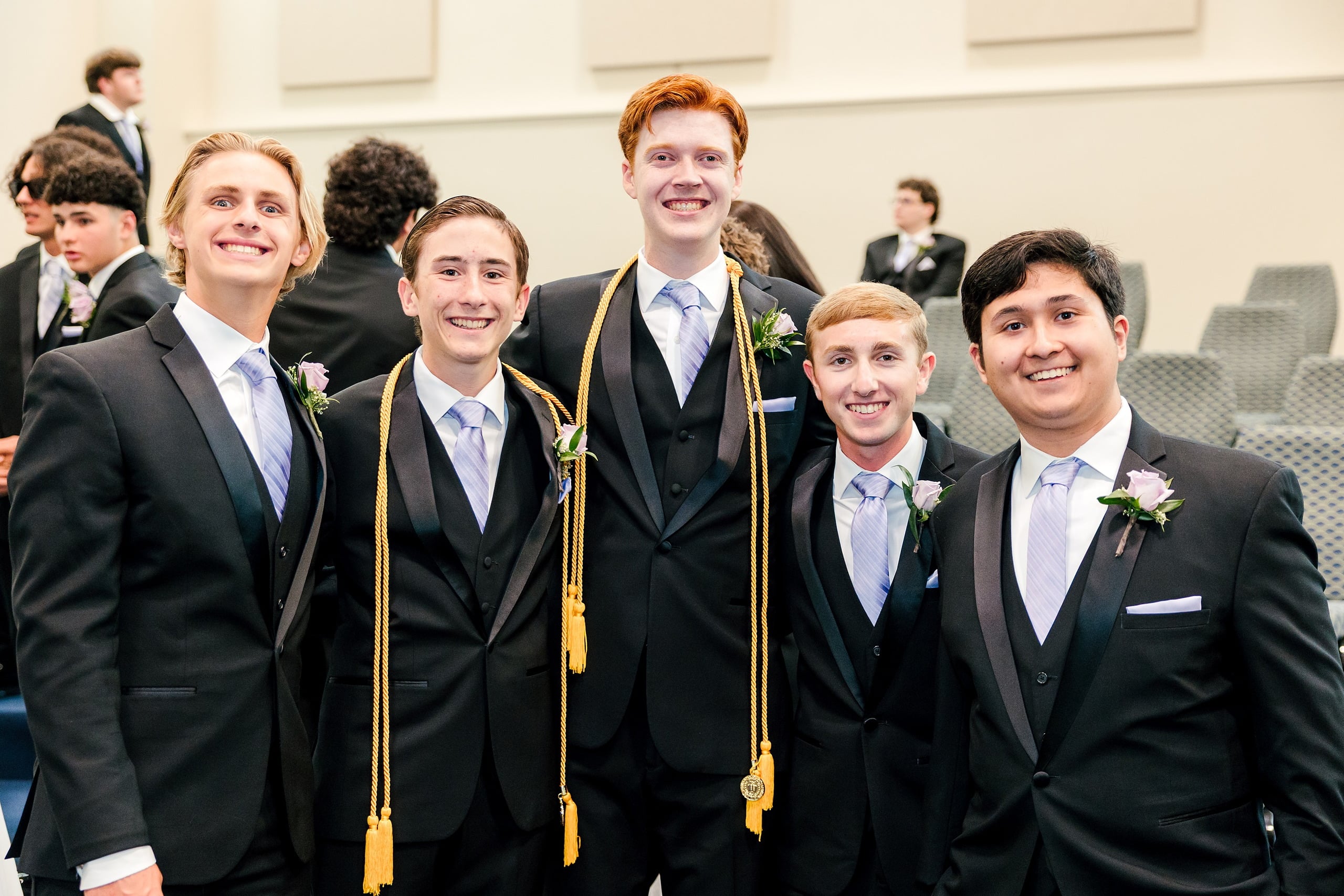 Christian High School Commencement 2025: Rise Up — 03 Five male graduates in black suits with white boutonnieres smile at the camera