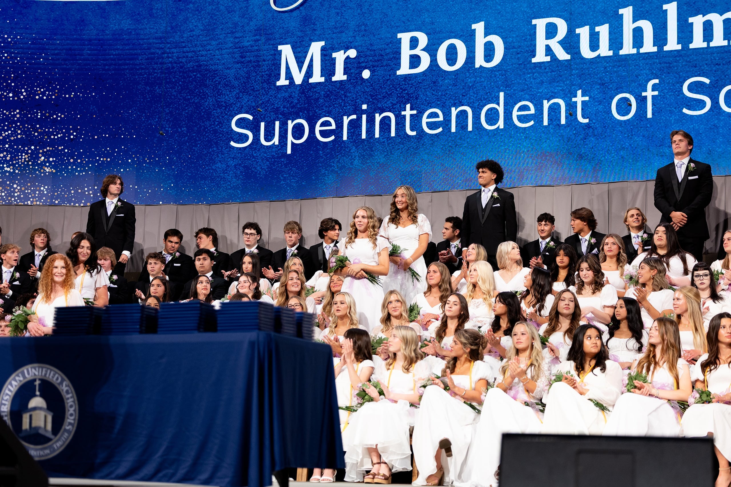Christian High School Commencement 2025: Rise Up — 20 School administrator in suit speaks at the podium to the assembled graduating class