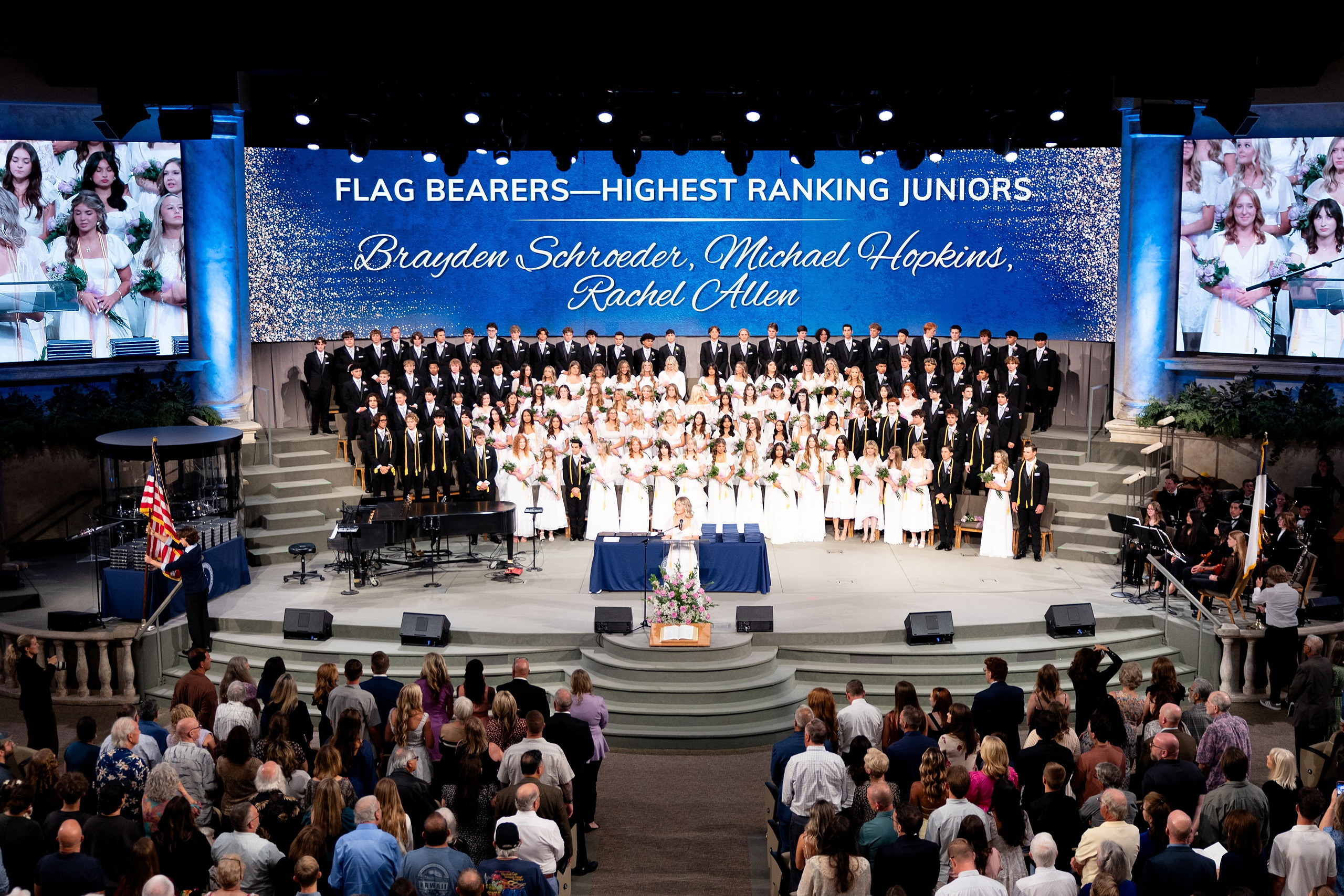 Christian High School Commencement 2025: Rise Up — 22 Junior flag bearers stand with the graduating class on the auditorium stage
