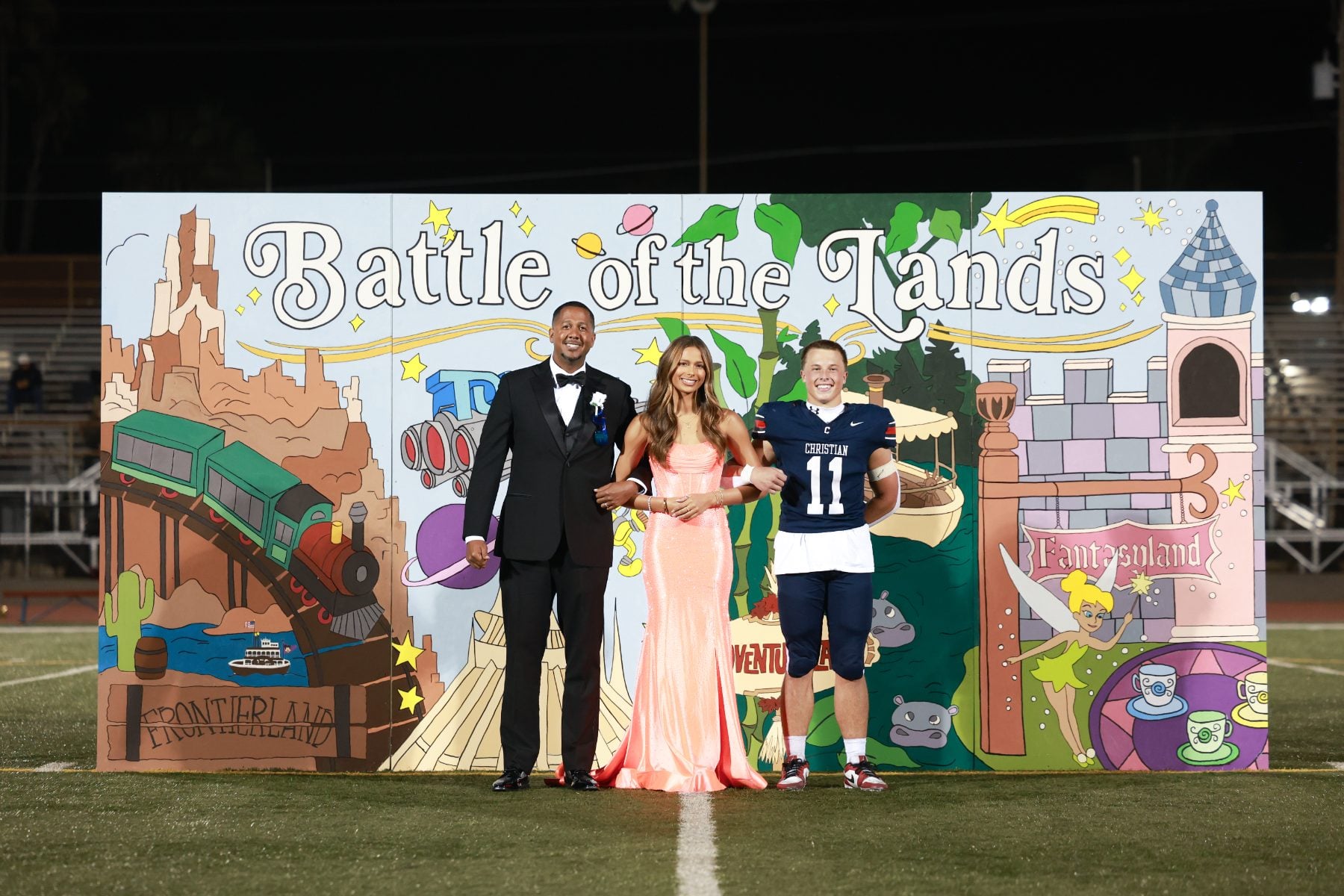 Homecoming court poses together in front of the Battle of the Lands mural