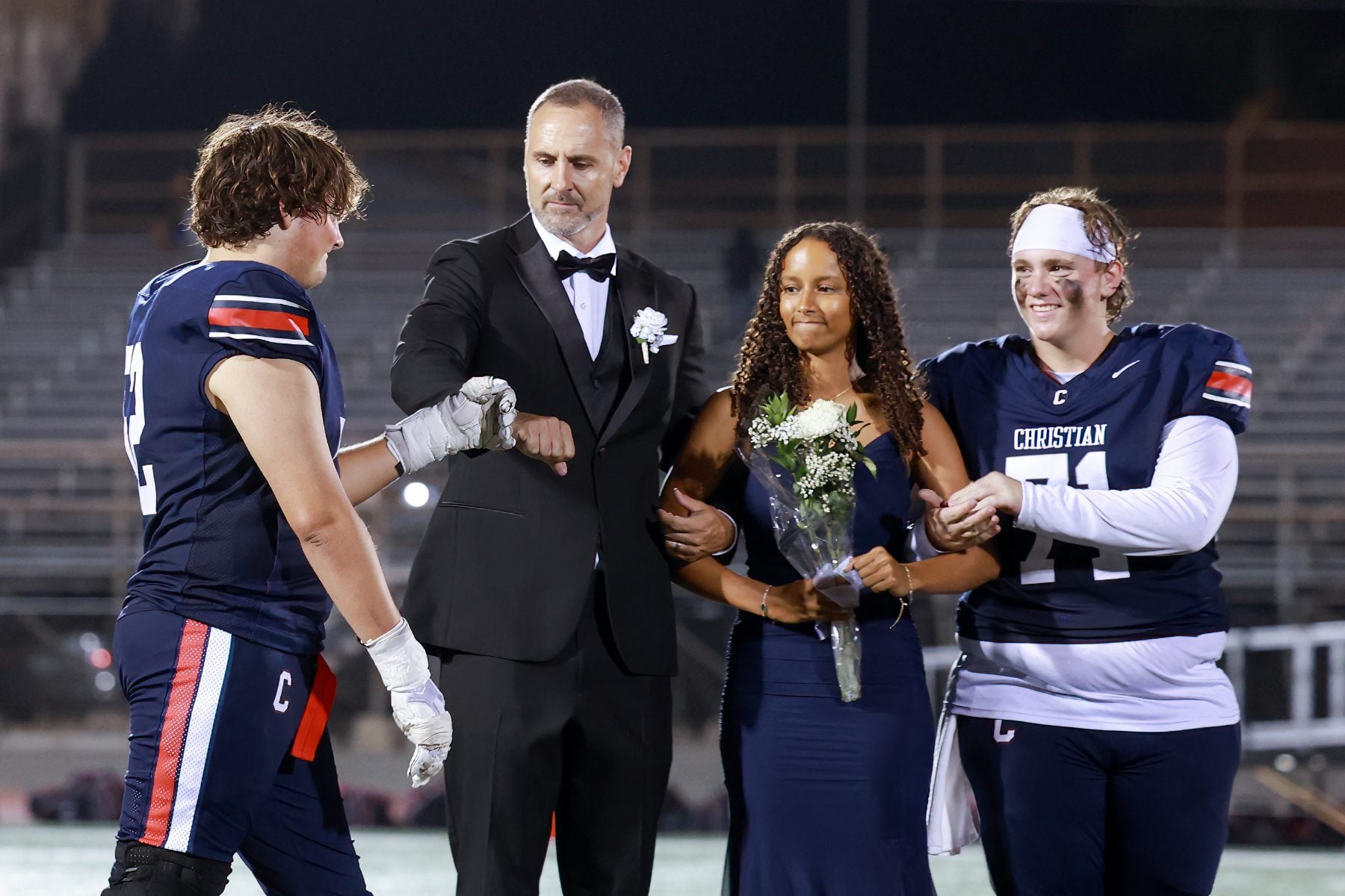 Football player fist-bumps a man in tuxedo during Christian High School homecoming court