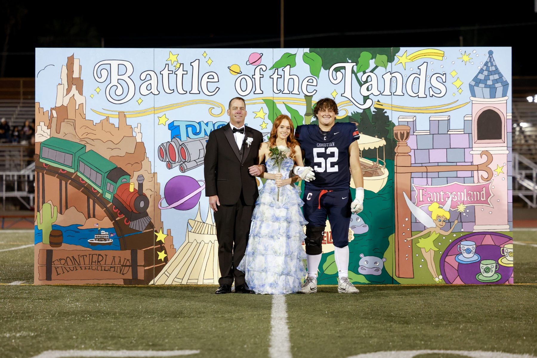 Homecoming trio smiles for a photo at the Battle of the Lands display