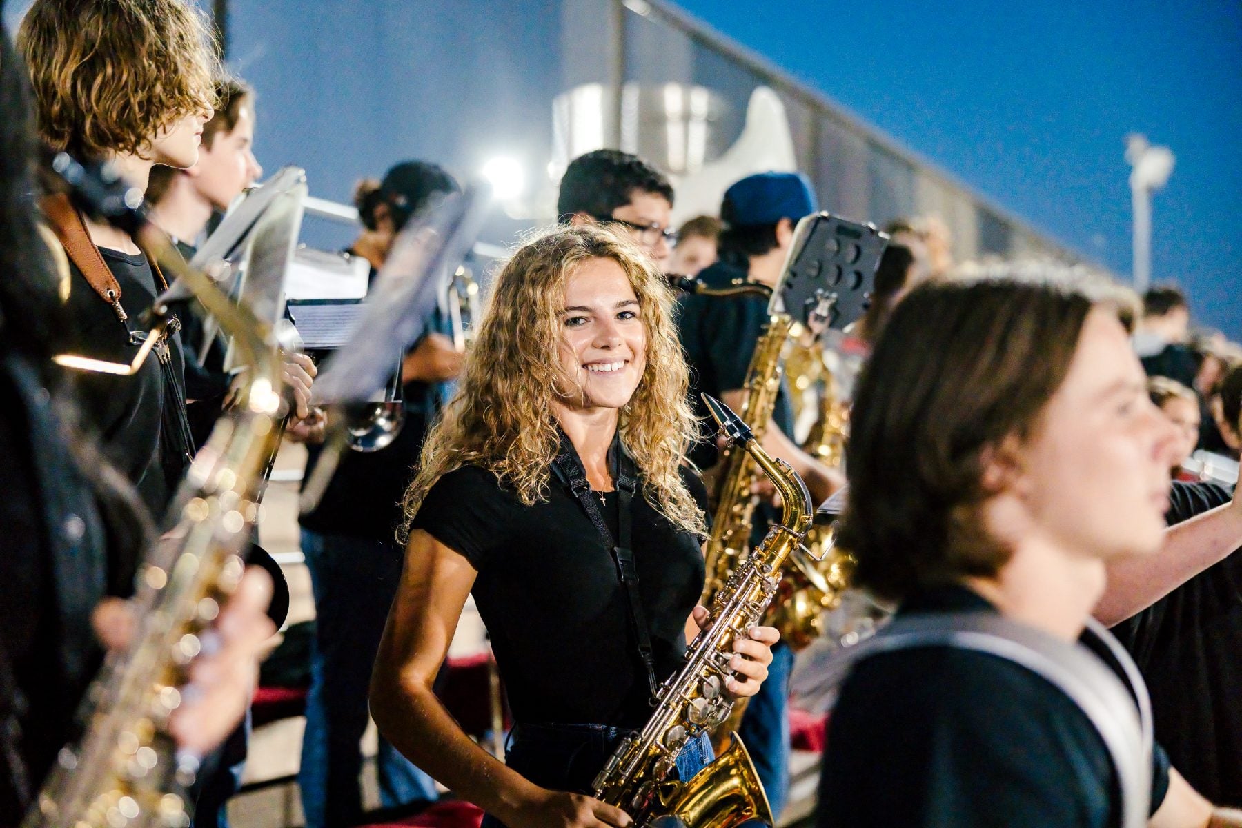 A student plays saxophone with the pep band at a Christian High School night game