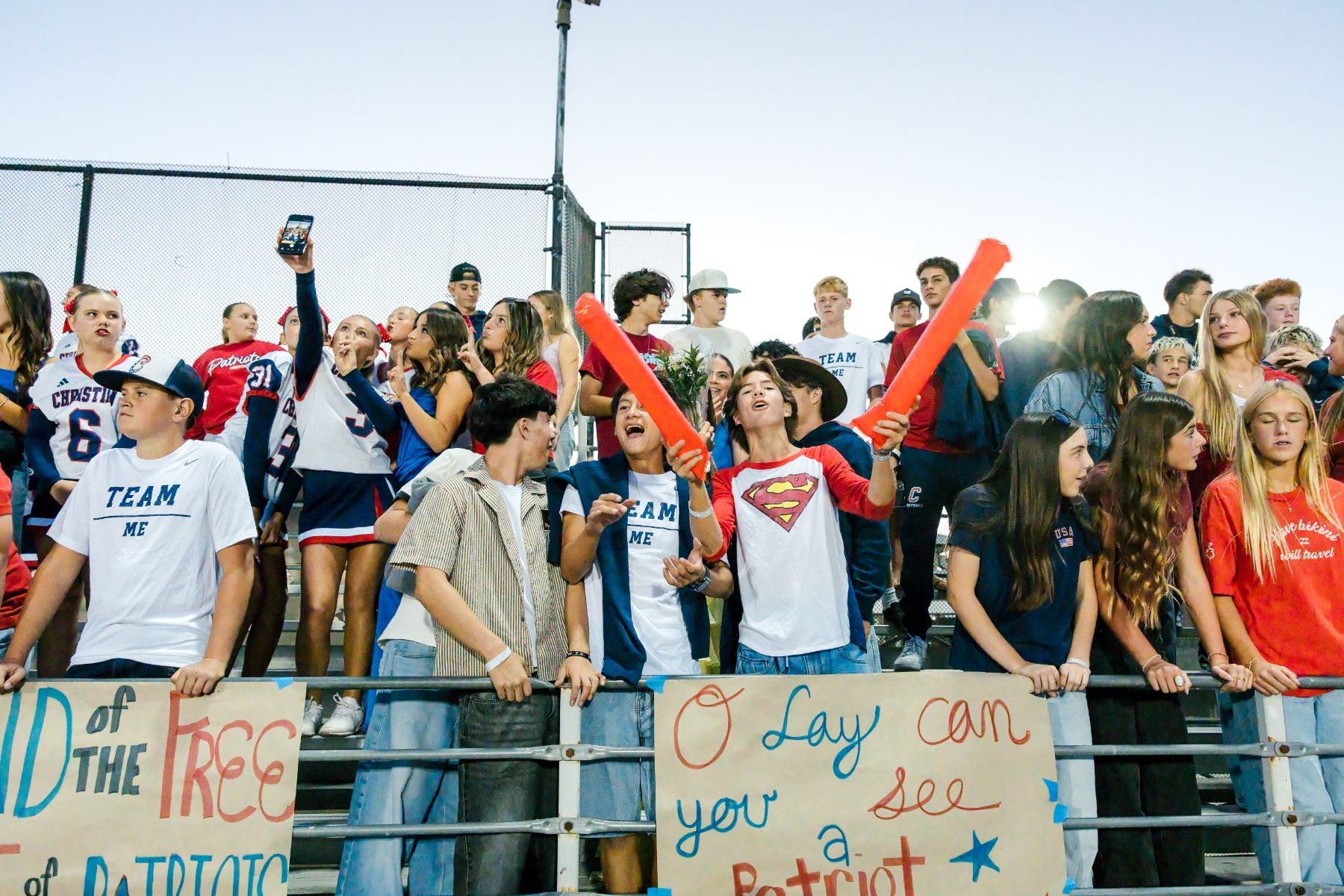 Student section fans cheer loudly holding handmade Homecoming signs