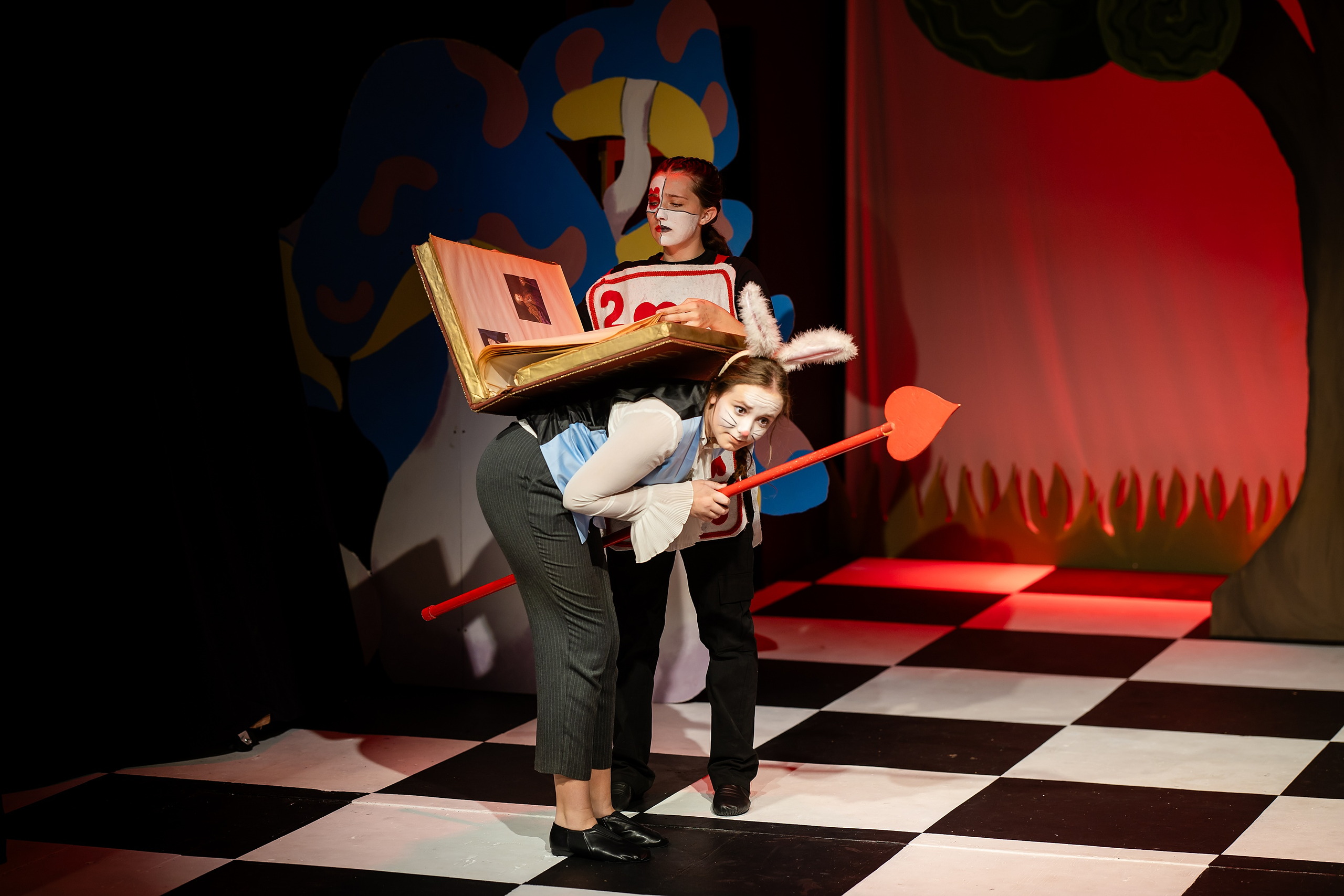 Curiouser and Curiouser! A Whimsical Journey with the Patriot Players — 09 Queen of Hearts character performs with student holding large paddle