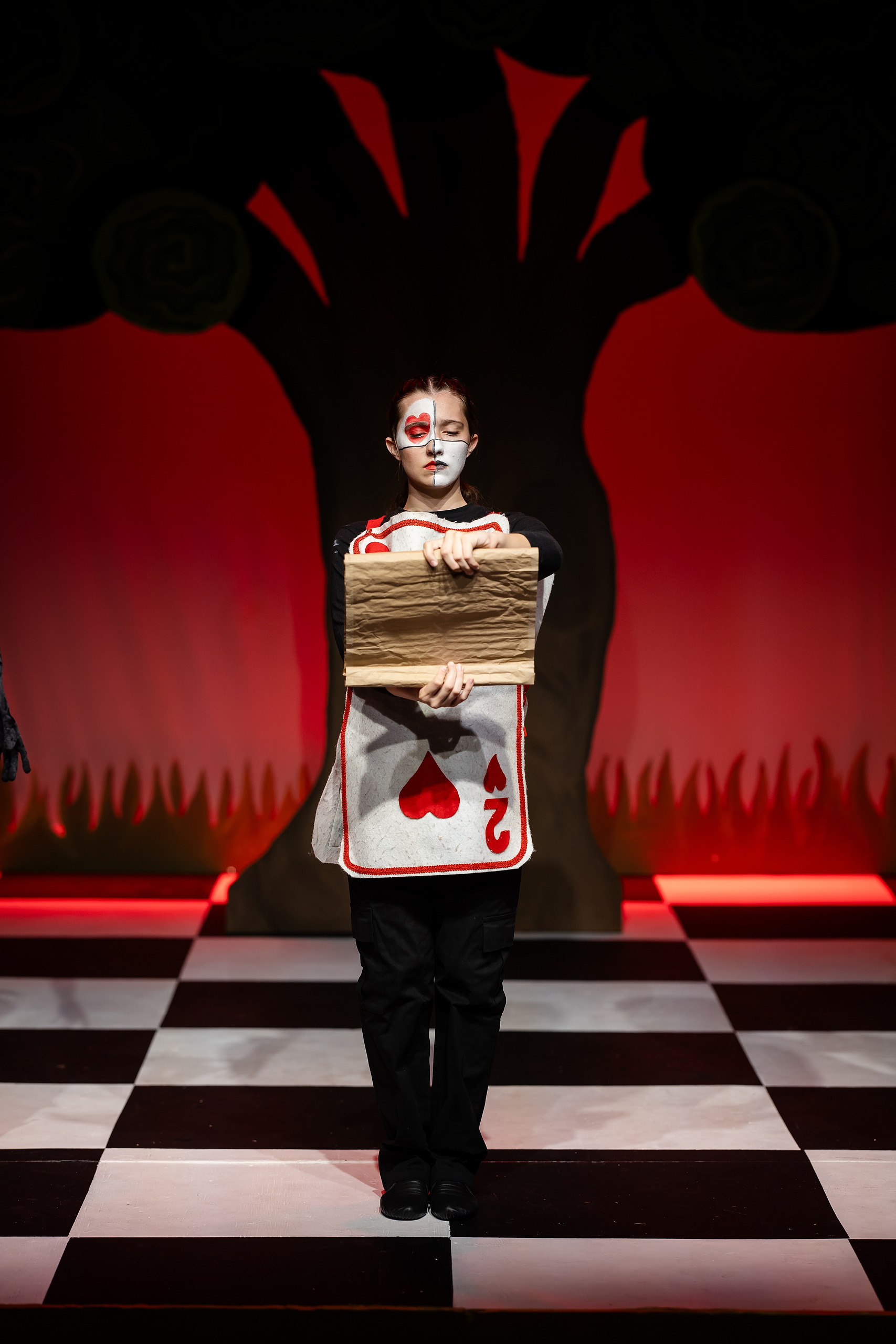 Curiouser and Curiouser! A Whimsical Journey with the Patriot Players — 10 Student in Alice costume spreads arms joyfully on whimsical stage