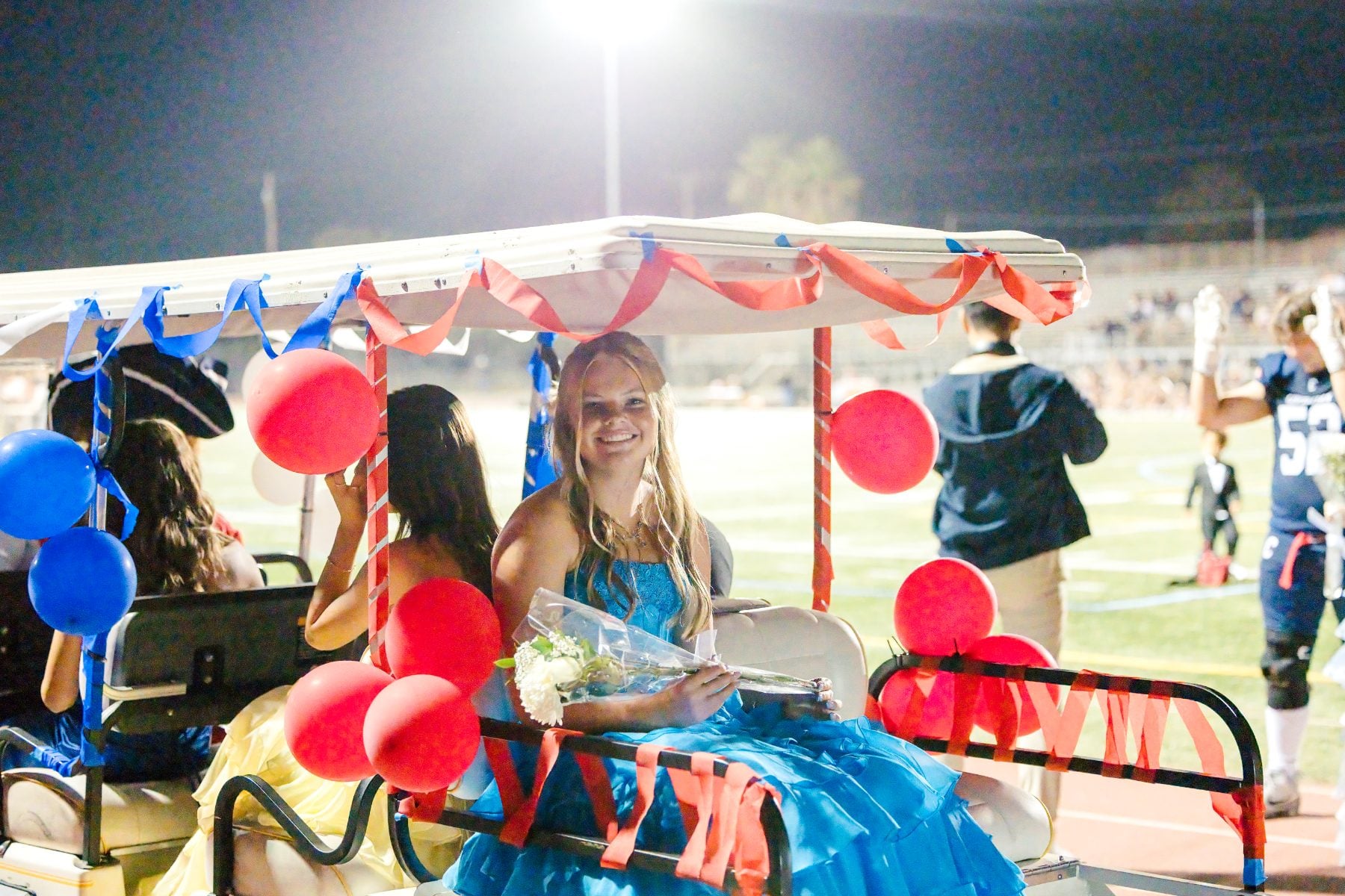 The homecoming queen rides in a decorated golf cart holding flowers