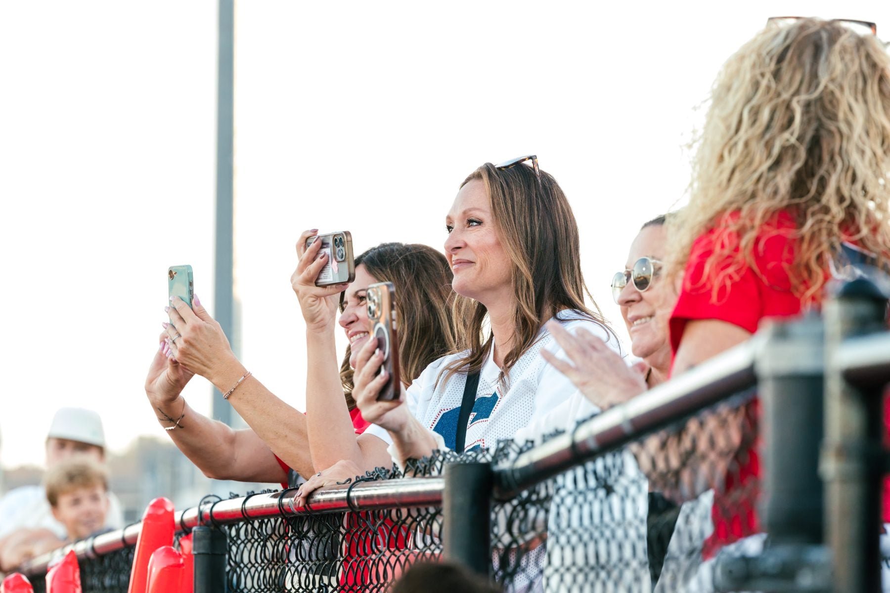 Parents cheer and photograph the game from the bleachers