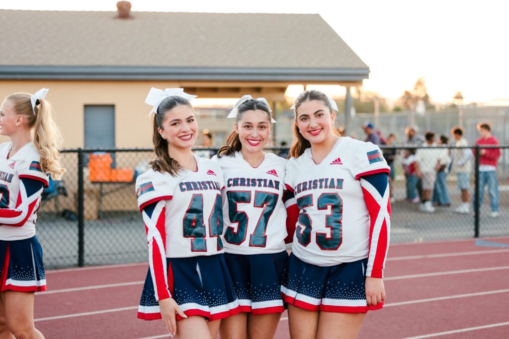 Three Christian High School cheerleaders smile together at homecoming