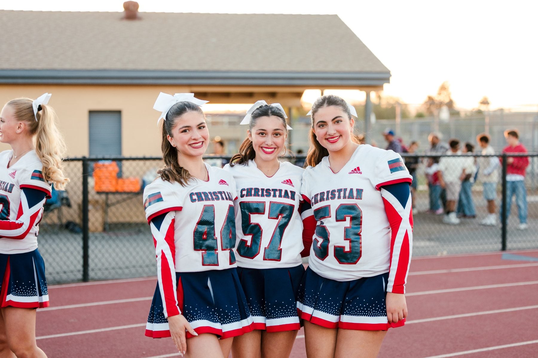 Three Christian High School cheerleaders smile together at homecoming