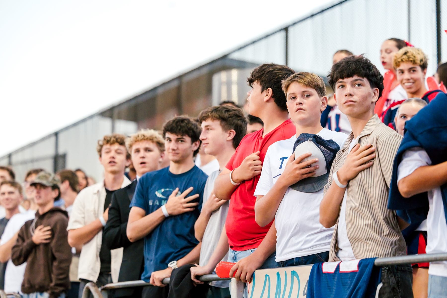 Students place hands over hearts during anthem at a Patriots football game