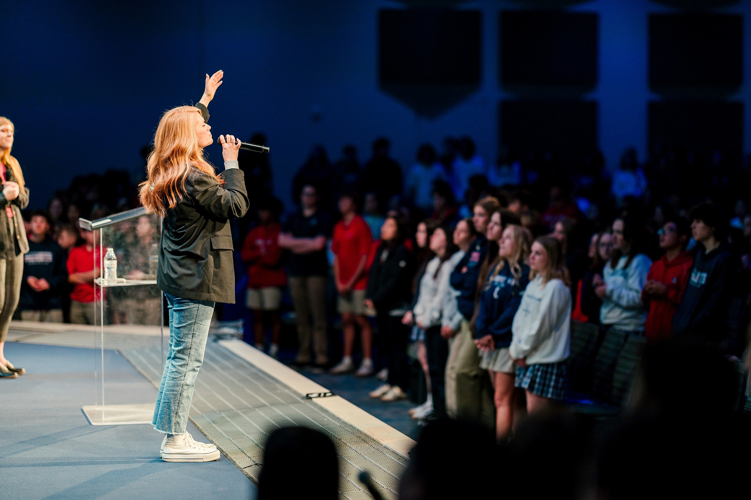 Spiritual Emphasis Week 2025 — 01 Female speaker with blonde hair in olive green jacket addresses students from chapel stage