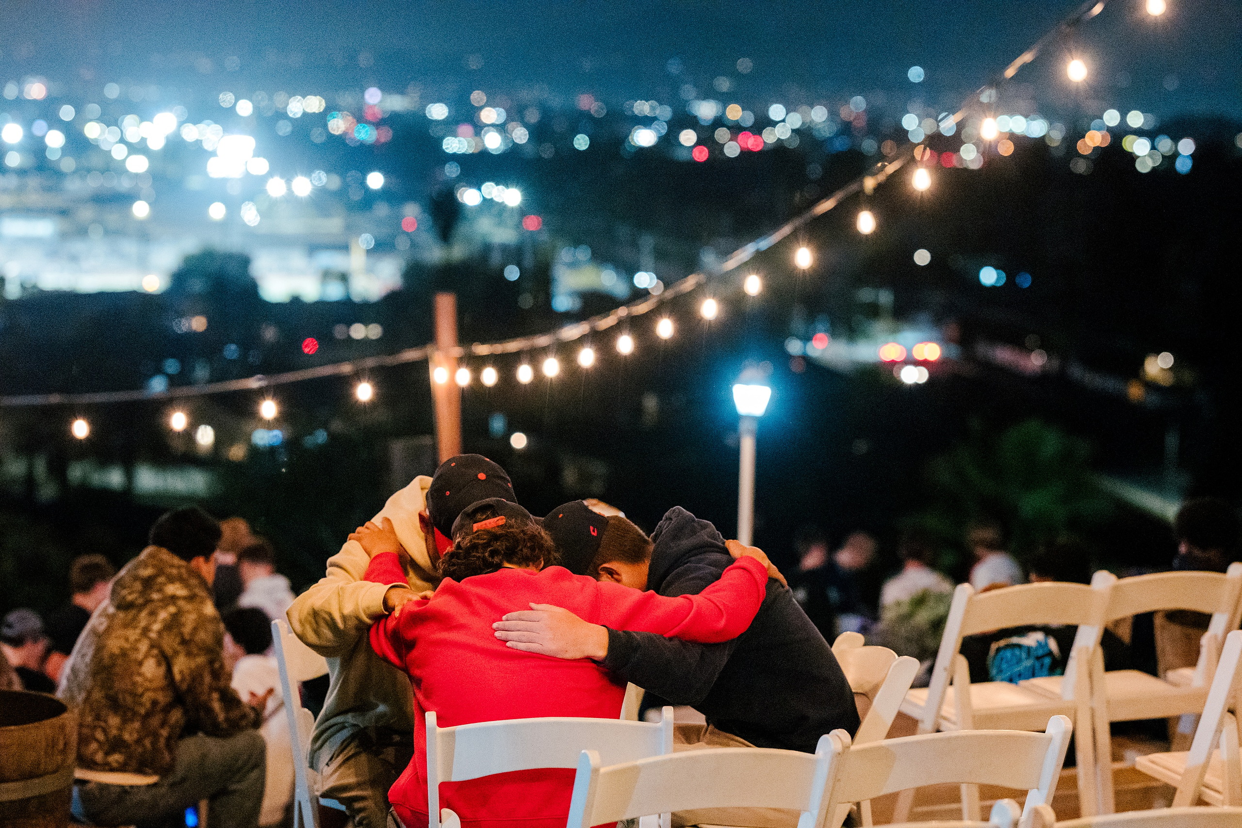 Spiritual Emphasis Week 2025 — 51 Students embrace together at evening worship with city lights behind