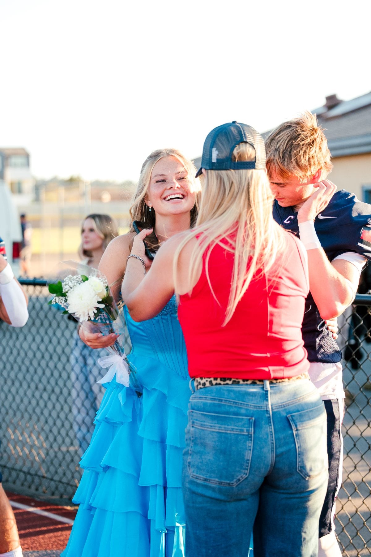 A student in a blue gown is congratulated by family at homecoming