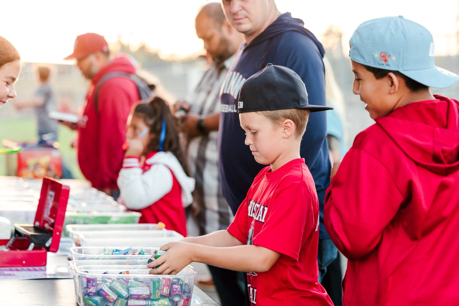 A young boy in a red shirt picks out prizes at a table