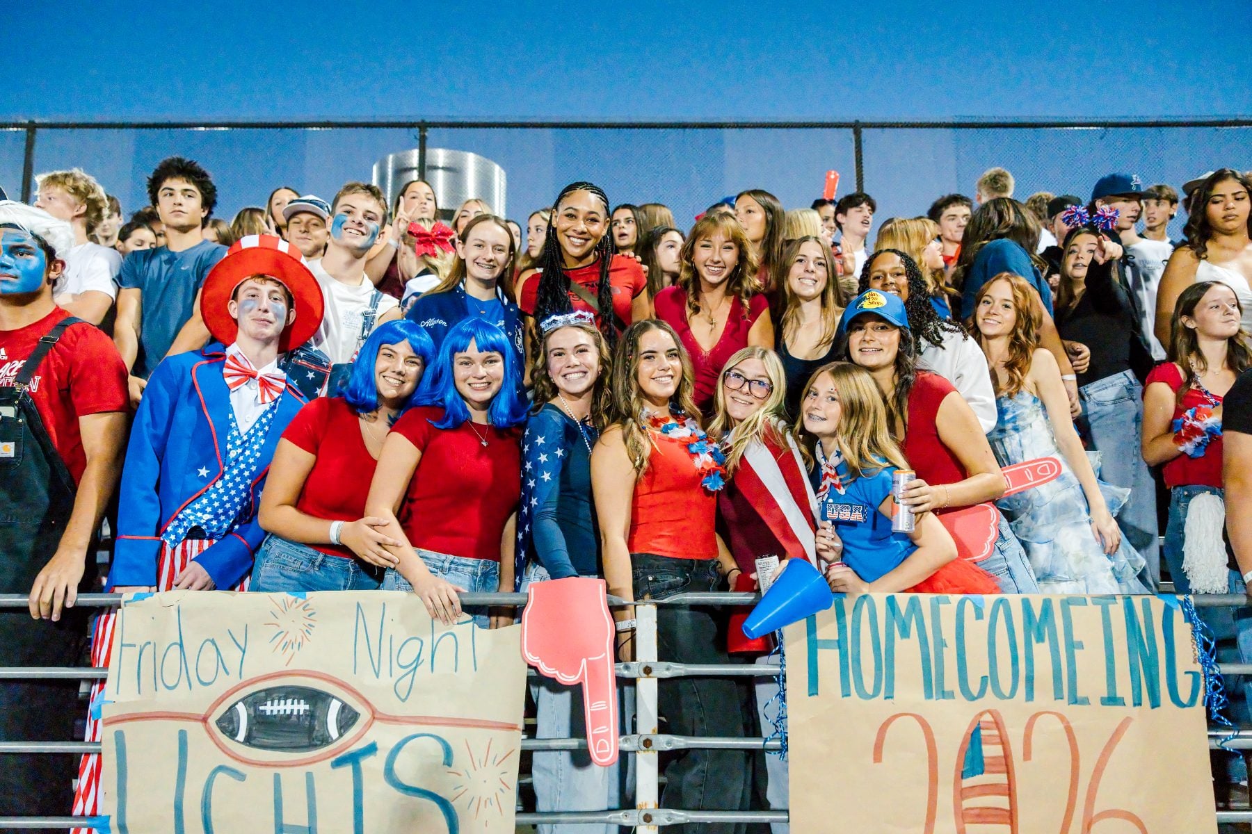A large group of students pose with homecoming signs in the bleachers