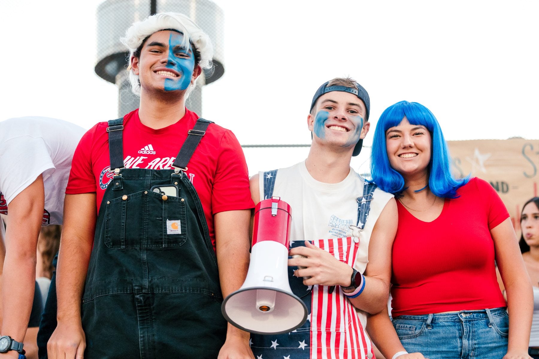 Three students in patriotic face paint and megaphone cheer at Christian High School