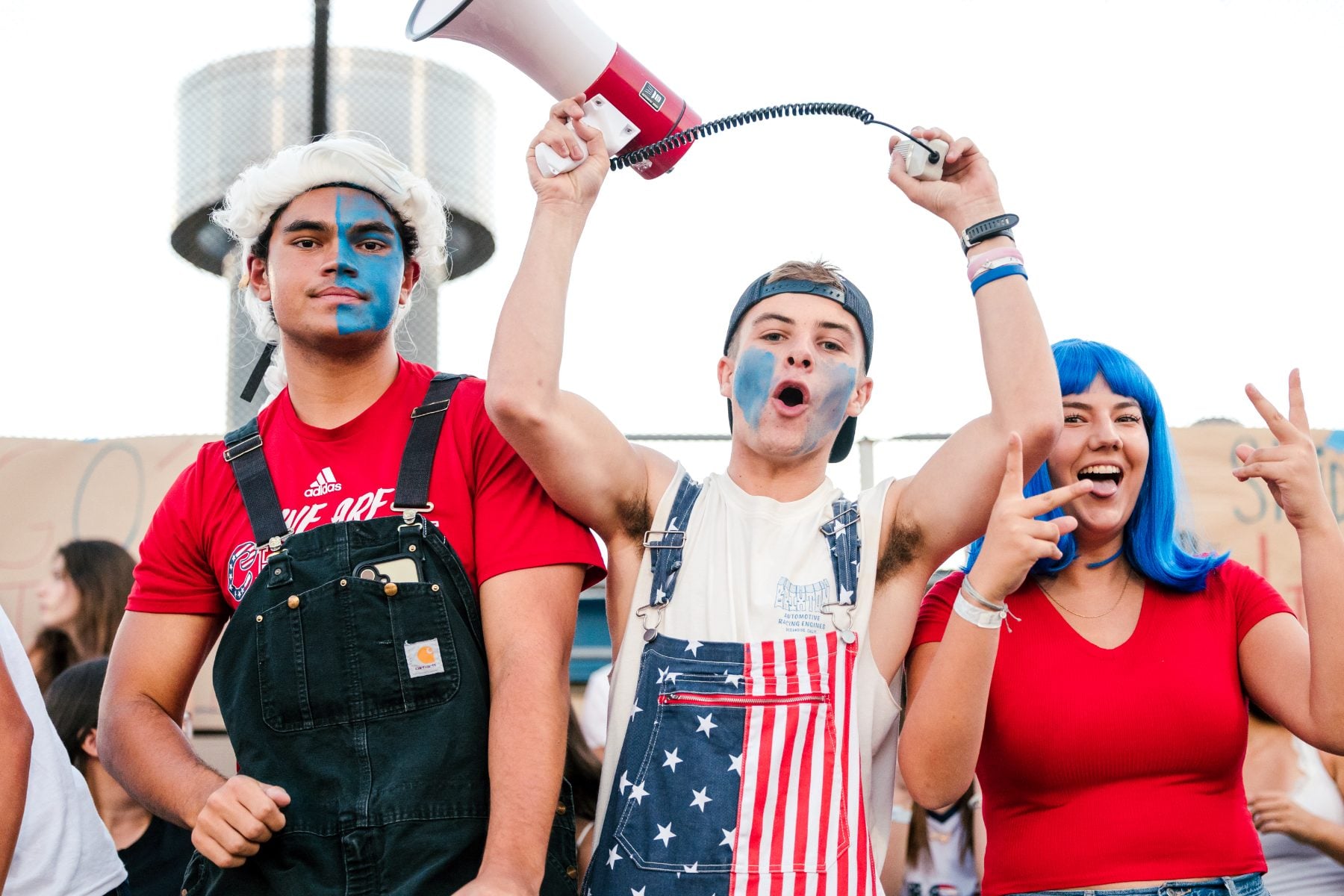 Students in patriotic face paint cheer with megaphone at homecoming