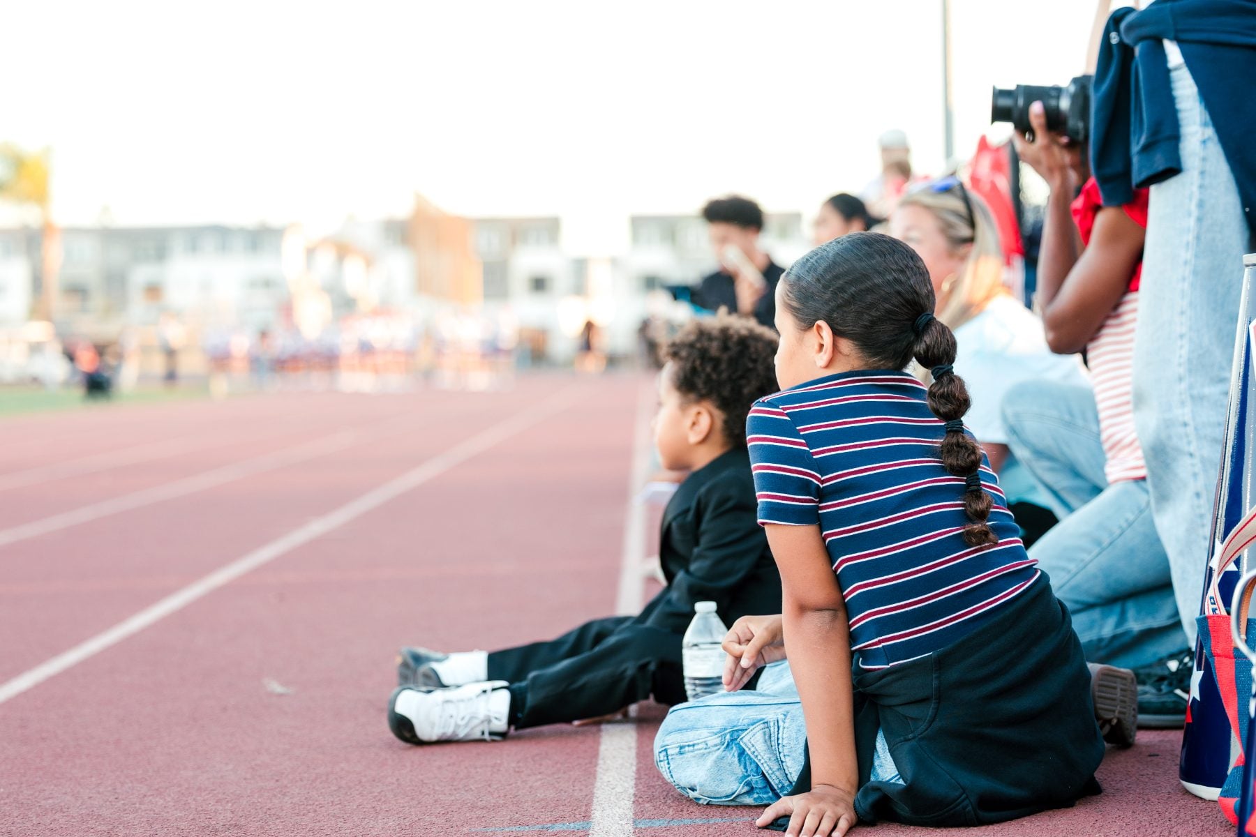 Children sit on the track watching the Homecoming festivities