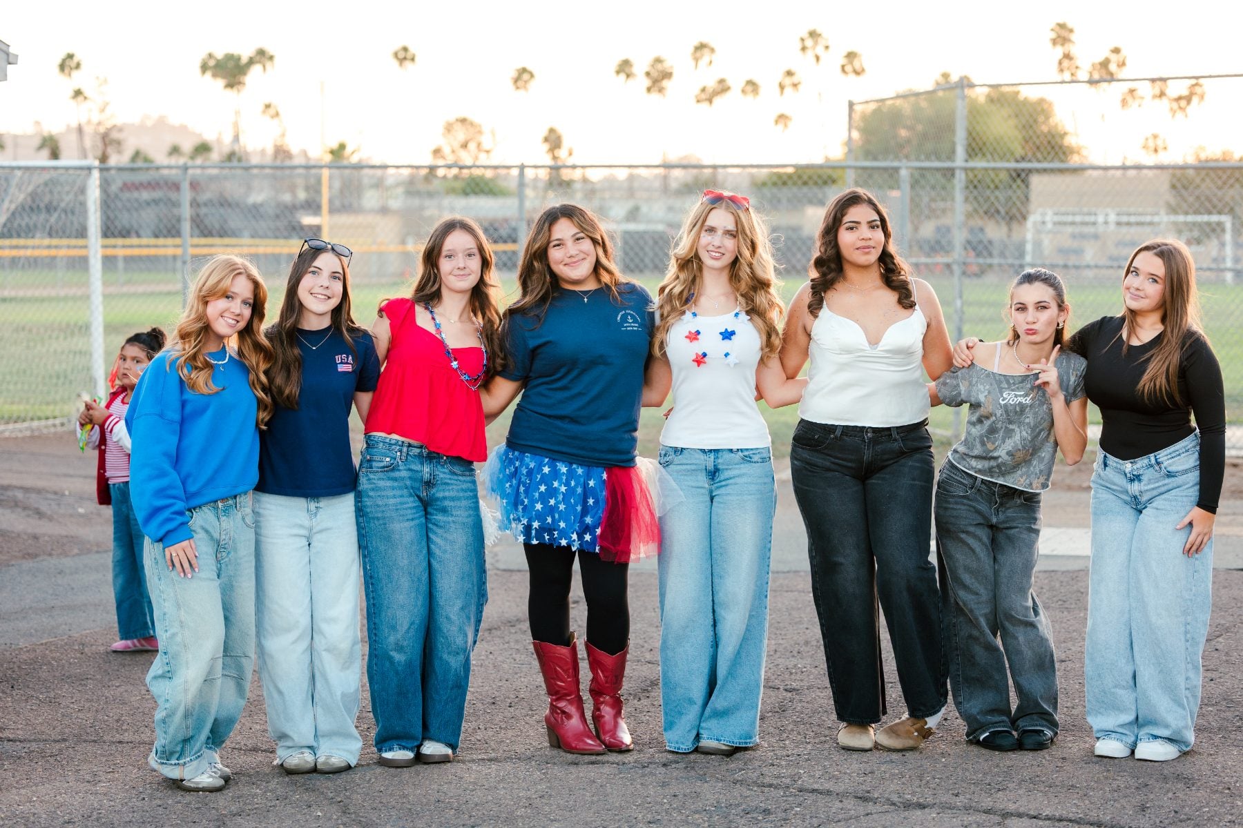 Group of teen girls pose together on the field at dusk