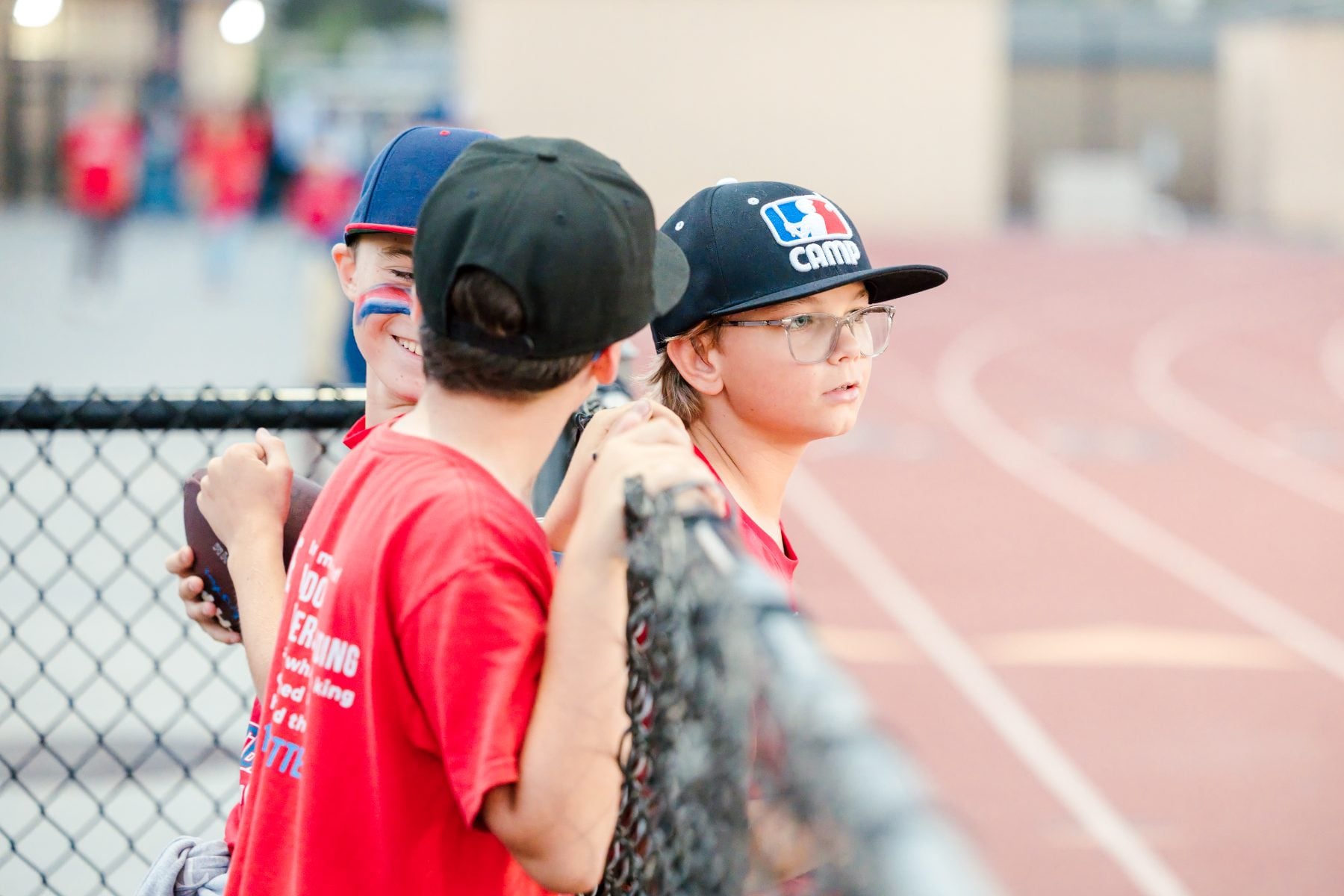 Young boys watch the Christian High School football game through the fence