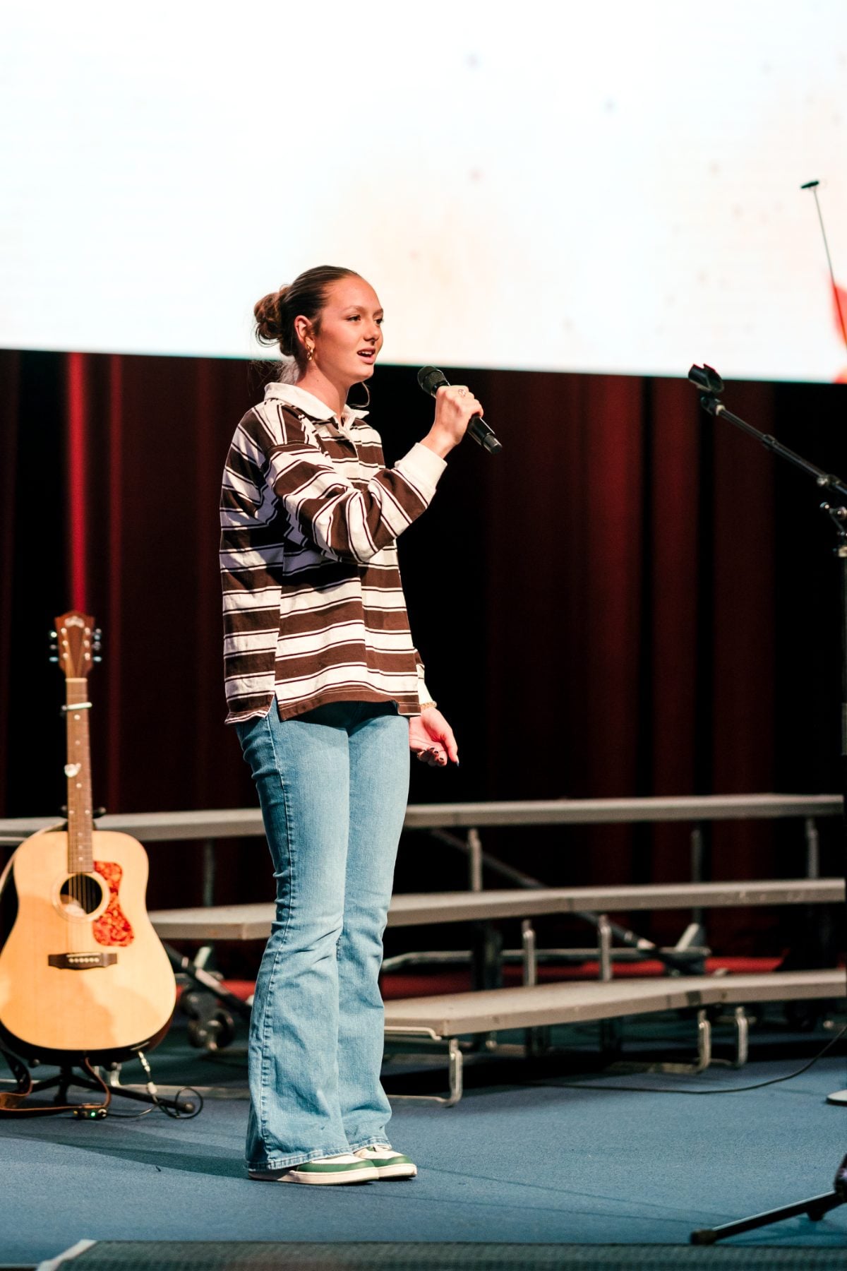 A student in a striped shirt performs a solo on stage