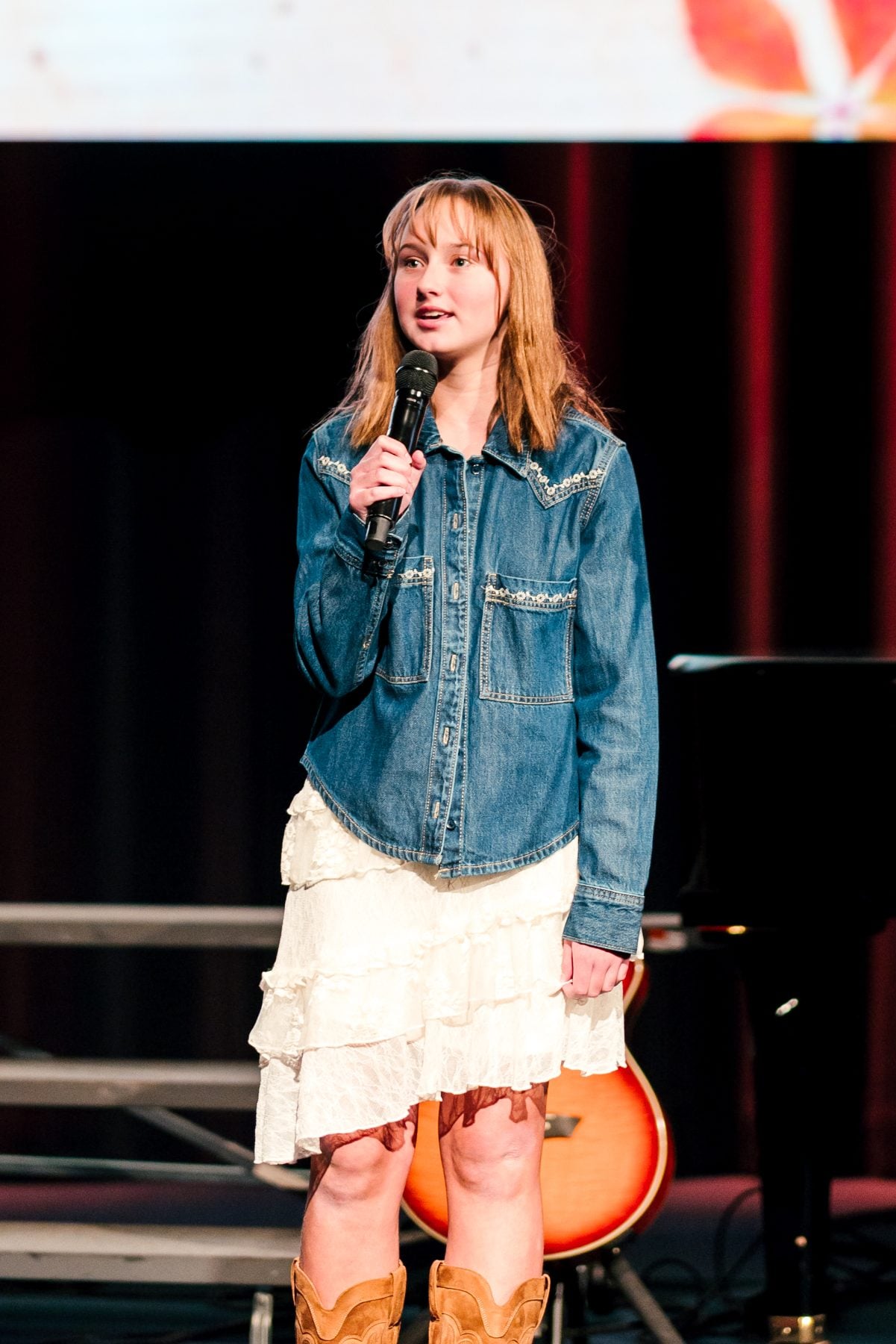 Student in denim jacket and boots performs solo at the Fall Choral Concert
