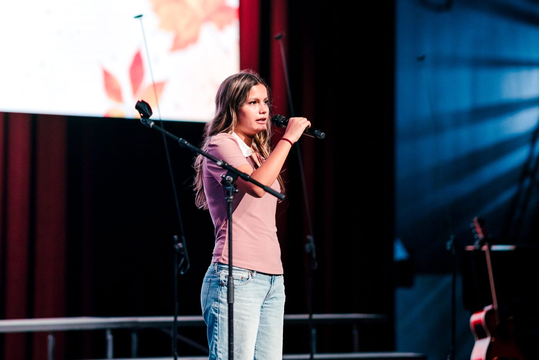 A student holds the mic stand while singing a solo number