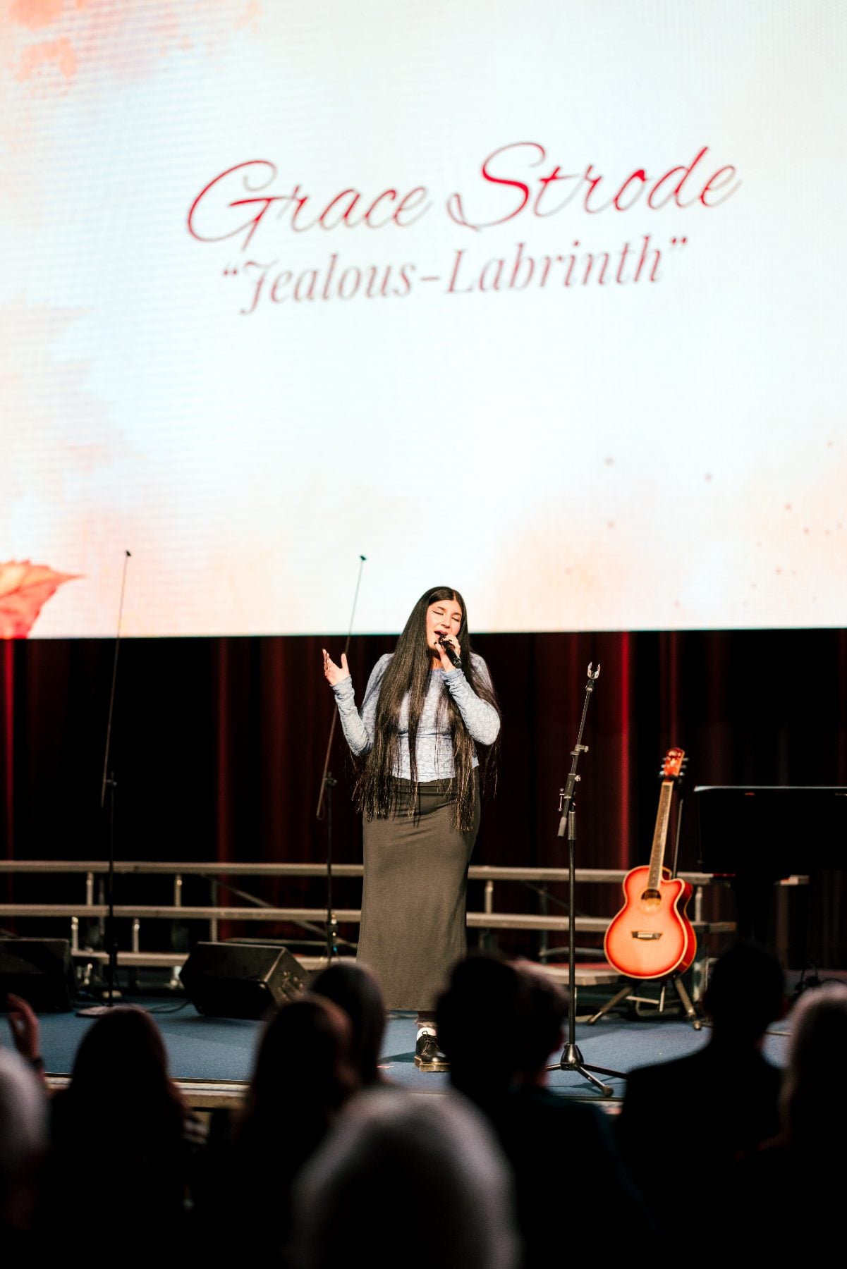A student in a long skirt sings passionately at the choral concert