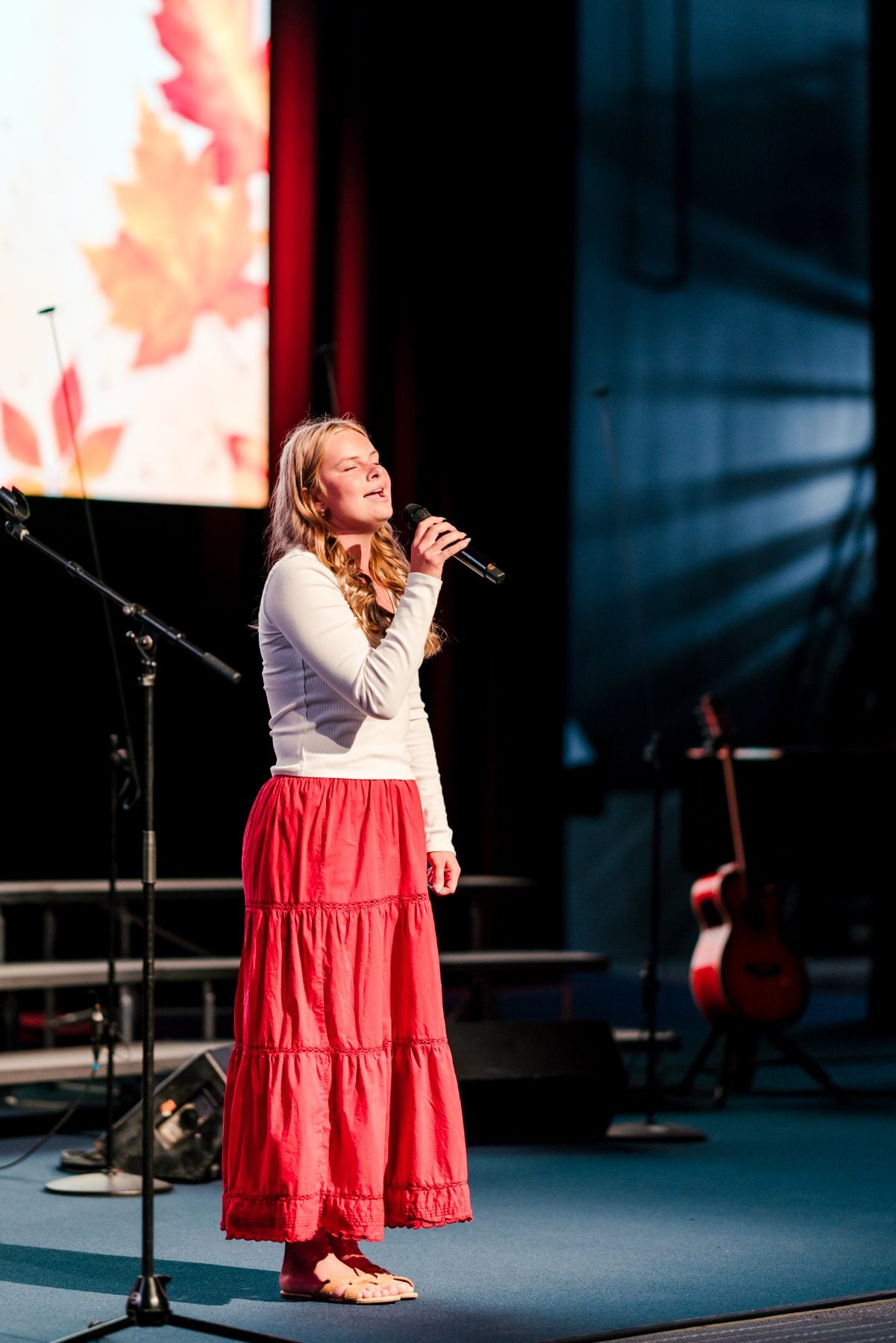 A student sings into a microphone on stage at the Fall Choral Concert