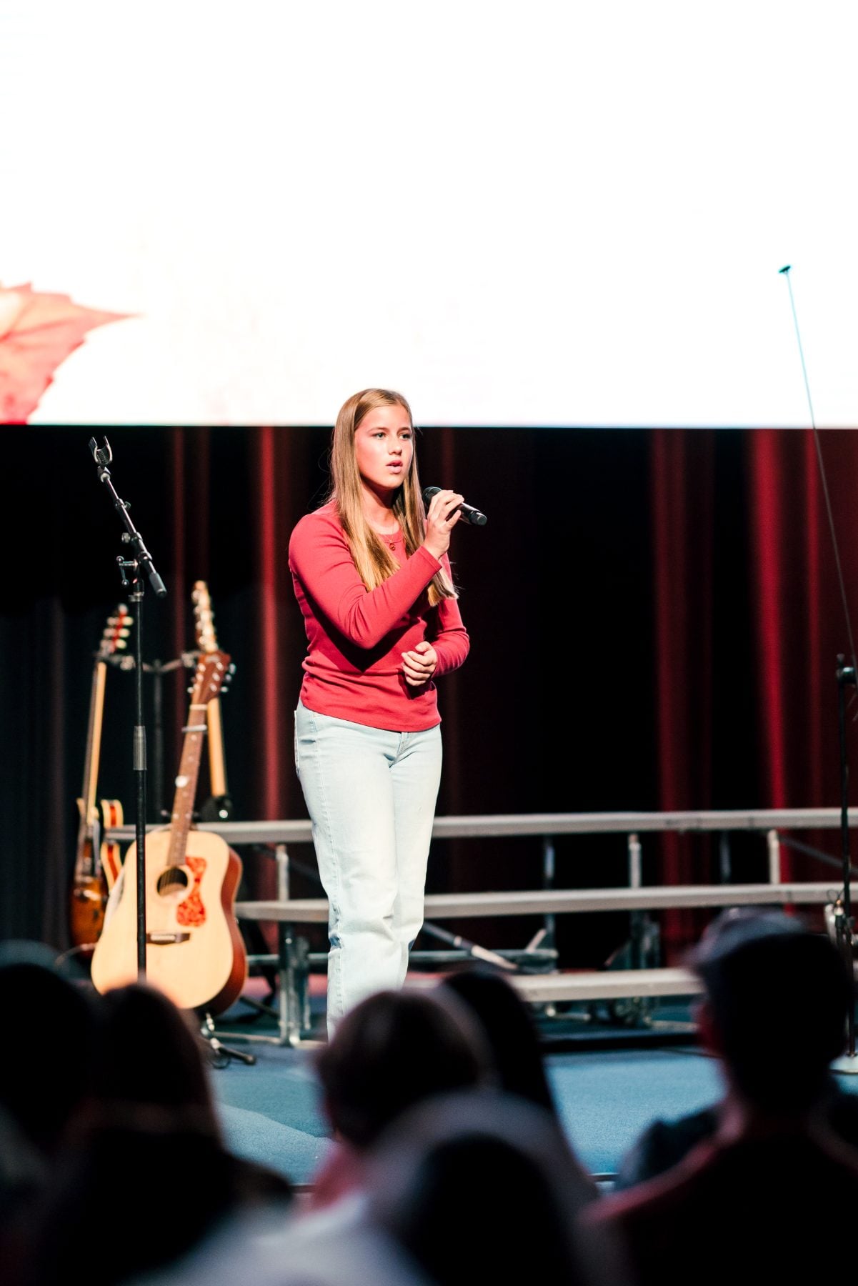 A student sings into a microphone on stage at the Event Center