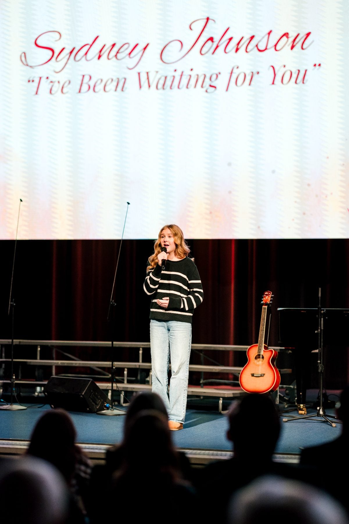 A student sings solo with an acoustic guitar displayed nearby