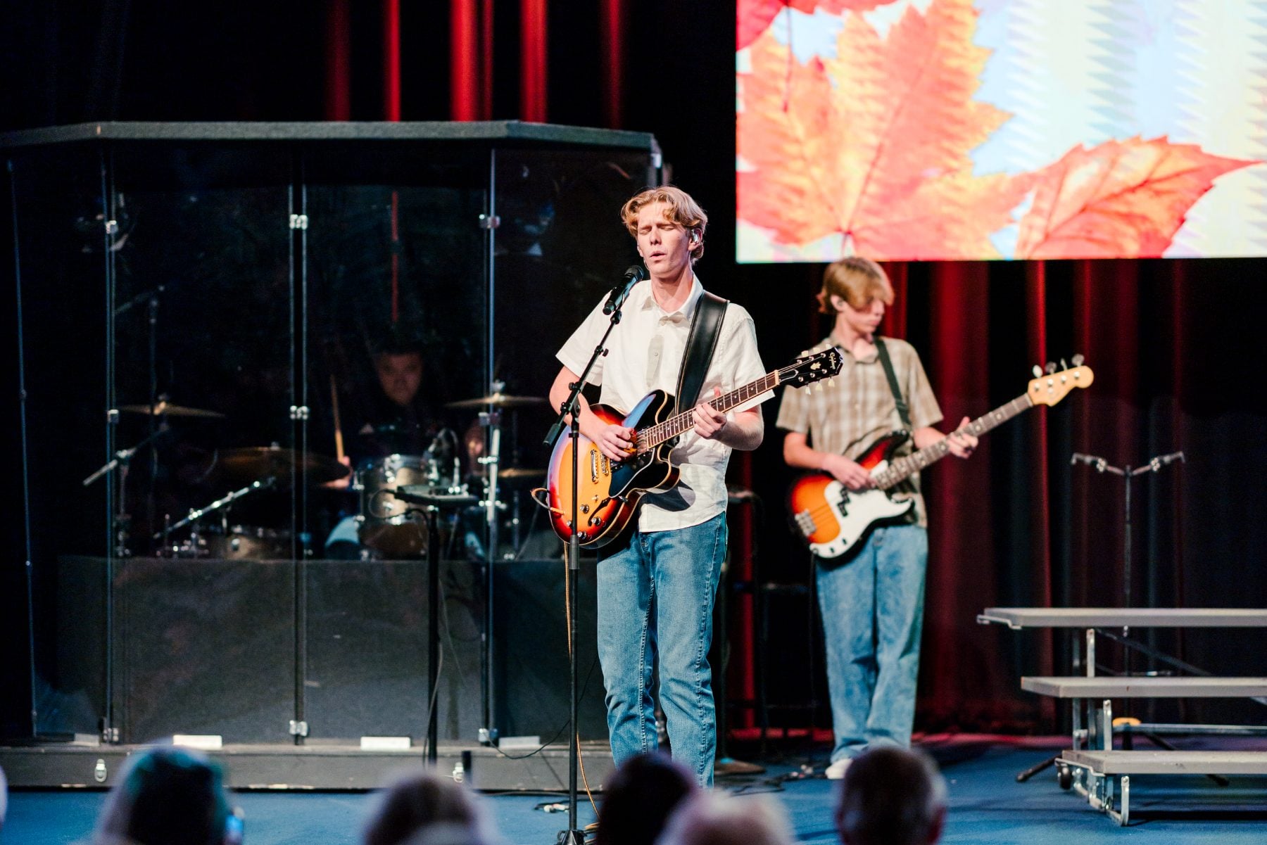 Two student guitarists and a drummer perform together on stage