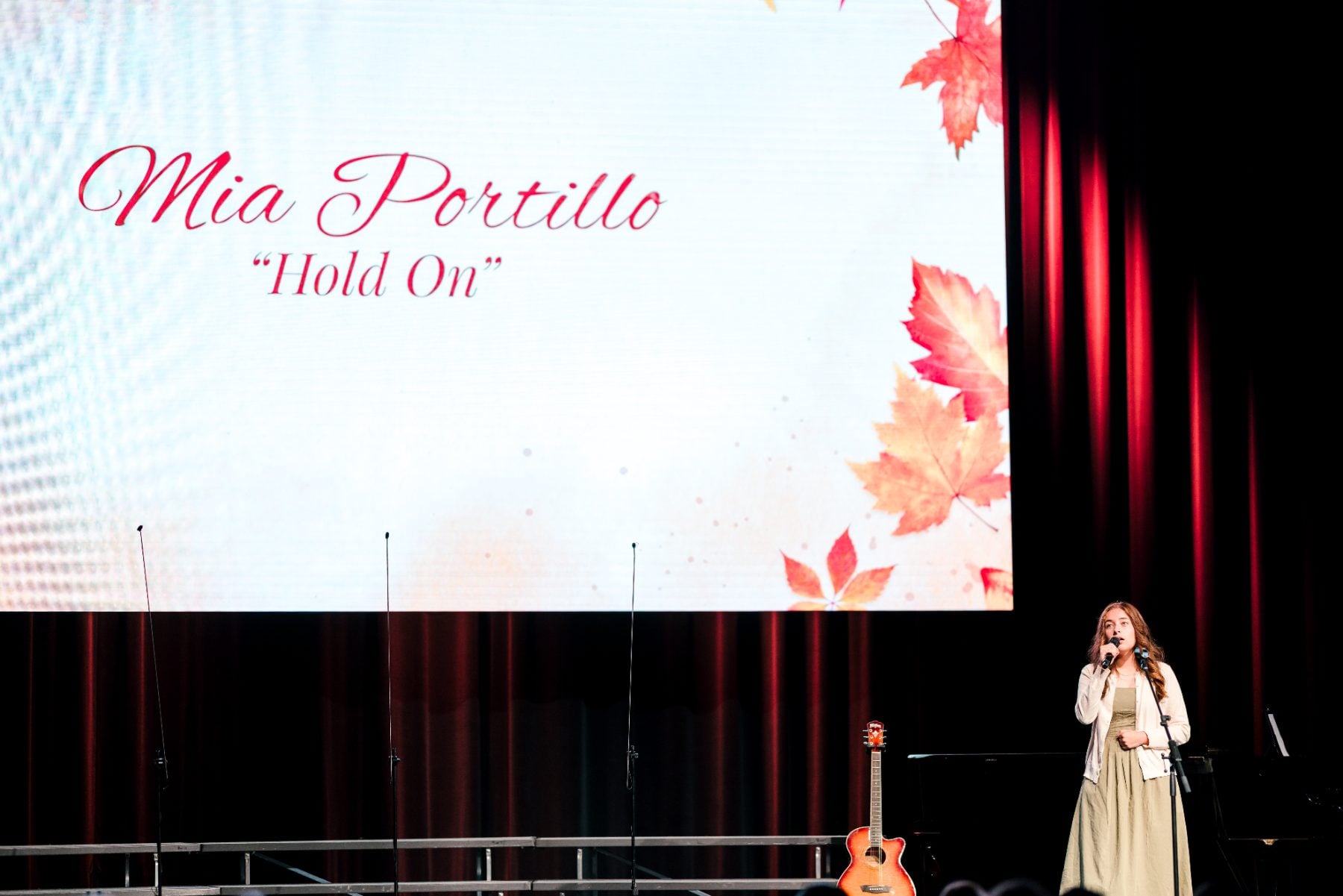 A student sings solo "Hold On" on stage at the Event Center.