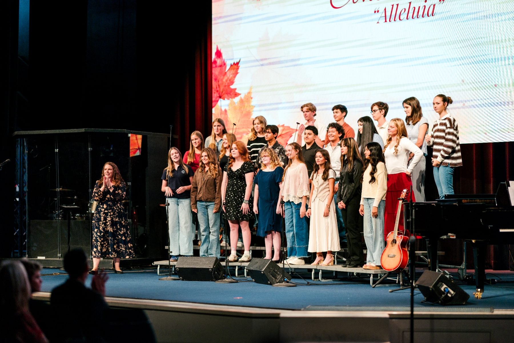 A teacher leads students singing "Alleluia" at the Event Center.
